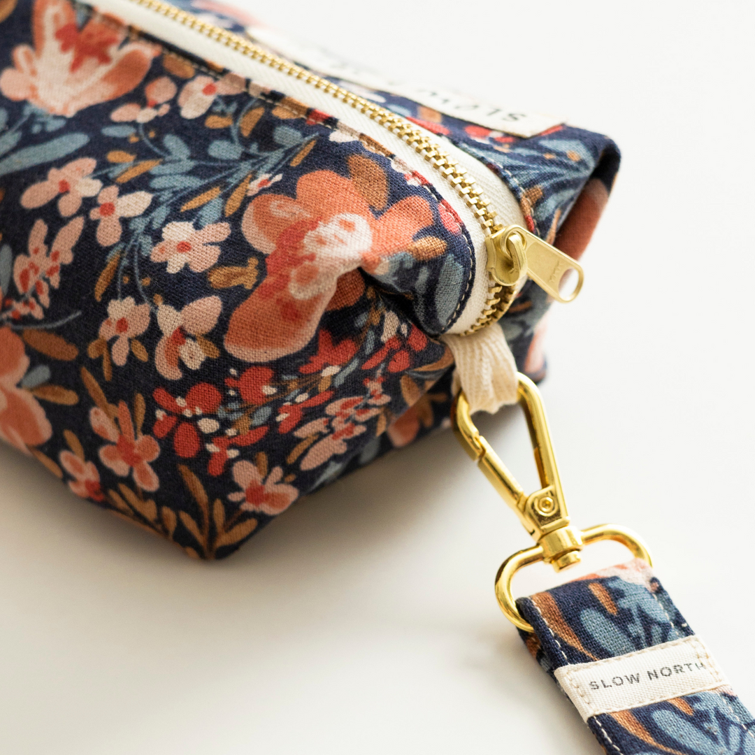 Floral travel pouch with pom-pom trim, ideal for organizing essentials.
