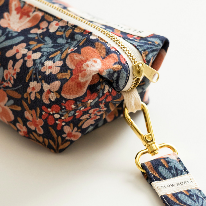 Floral travel pouch with pom-pom trim, ideal for organizing essentials.