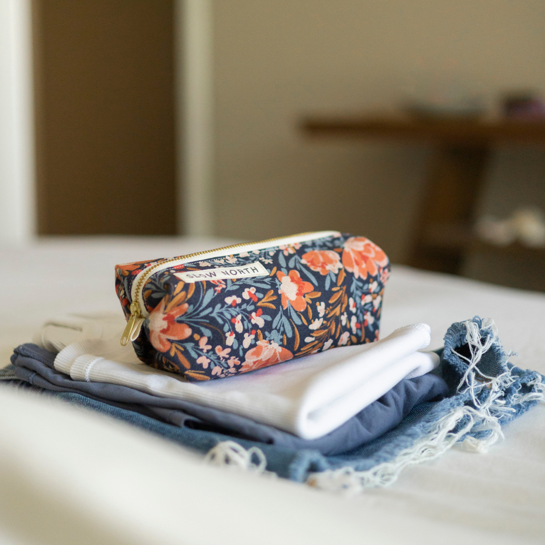 Floral travel pouch with colorful embroidery detail and zipper closure.