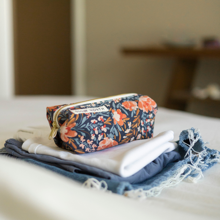Floral travel pouch with colorful embroidery detail and zipper closure.