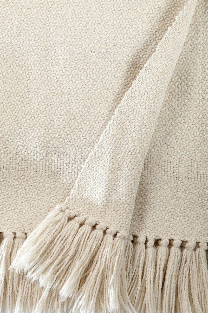 Close-up of the ivory twill weave and hand-tied fringe on a merino and llama wool throw.