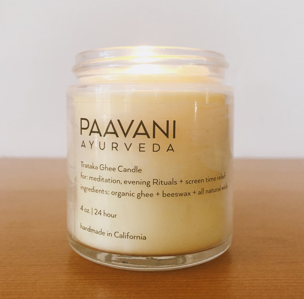 Organic ghee trataka meditation candle, glowing on a simple surface.