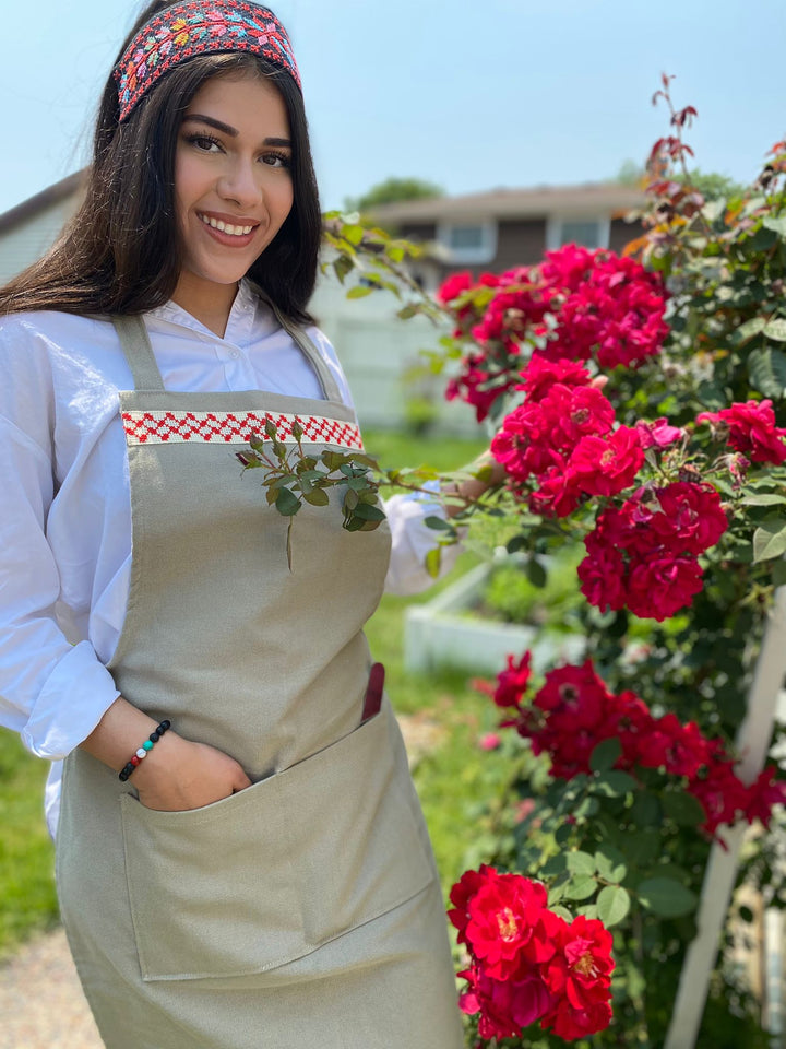 Sage-green cotton-blend full-length apron with a red-and-white tatreez kuffiyeh band across the chest.