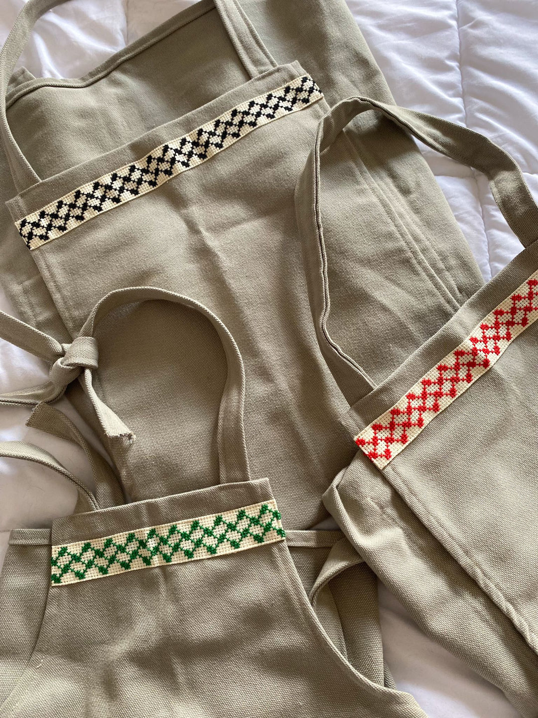 Close-up of the black-and-white kuffiyeh cross-stitch band on a grey apron.