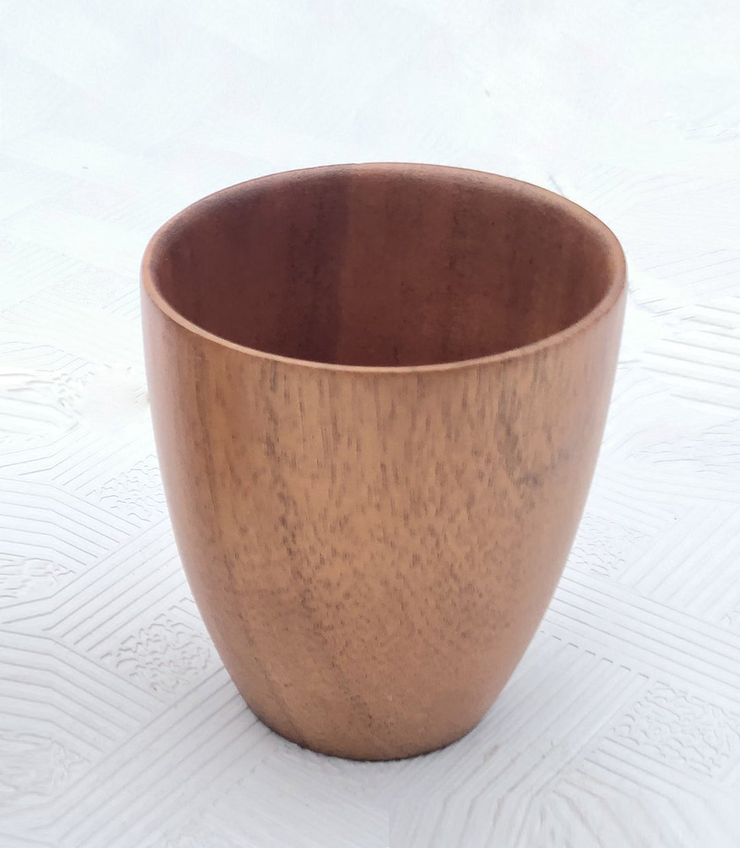 Handcrafted acacia wood cup with natural wood grain and a smooth, rounded shape.