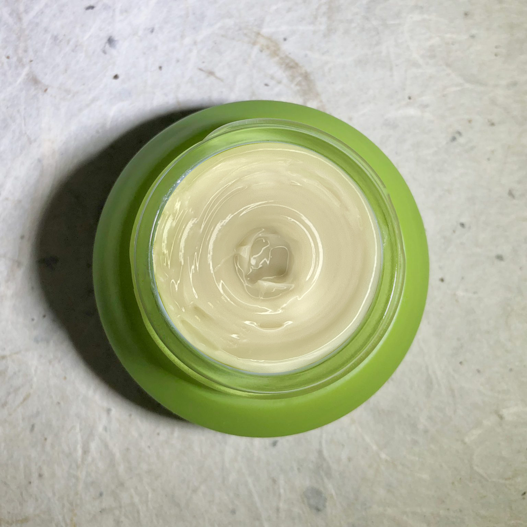 Herban Wisdom eye cream jar with the cream inside and natural packaging.