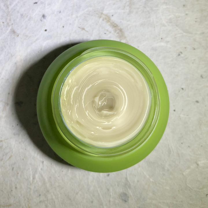 Herban Wisdom eye cream jar with the cream inside and natural packaging.