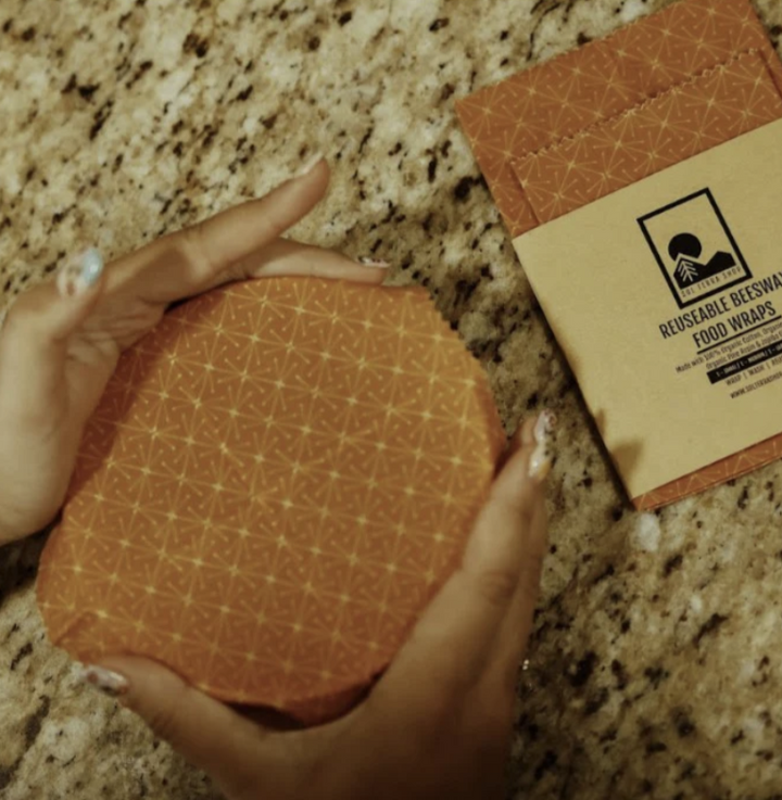 Reusable organic beeswax food wraps in various sizes on a kitchen surface.