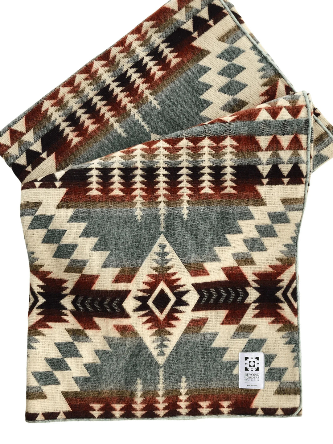 Handwoven Andean throw blanket in cream, rust, and slate with a sage-mint bound edge, folded.