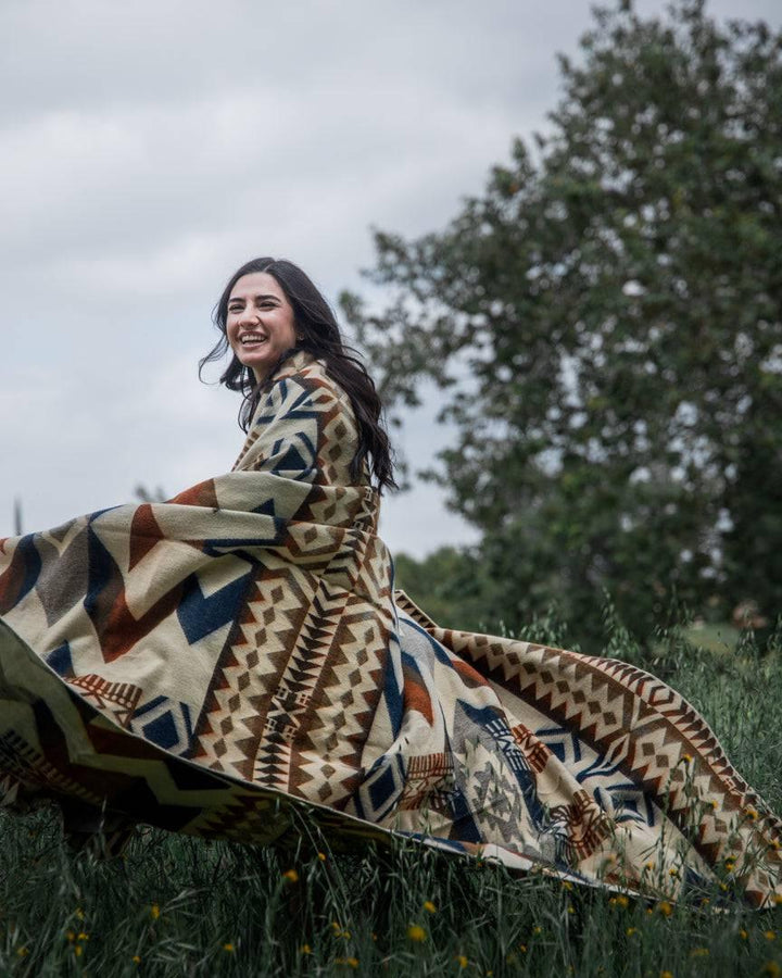 Handwoven Awa Earth blanket in navy, slate-grey, brown, and rust on cream.