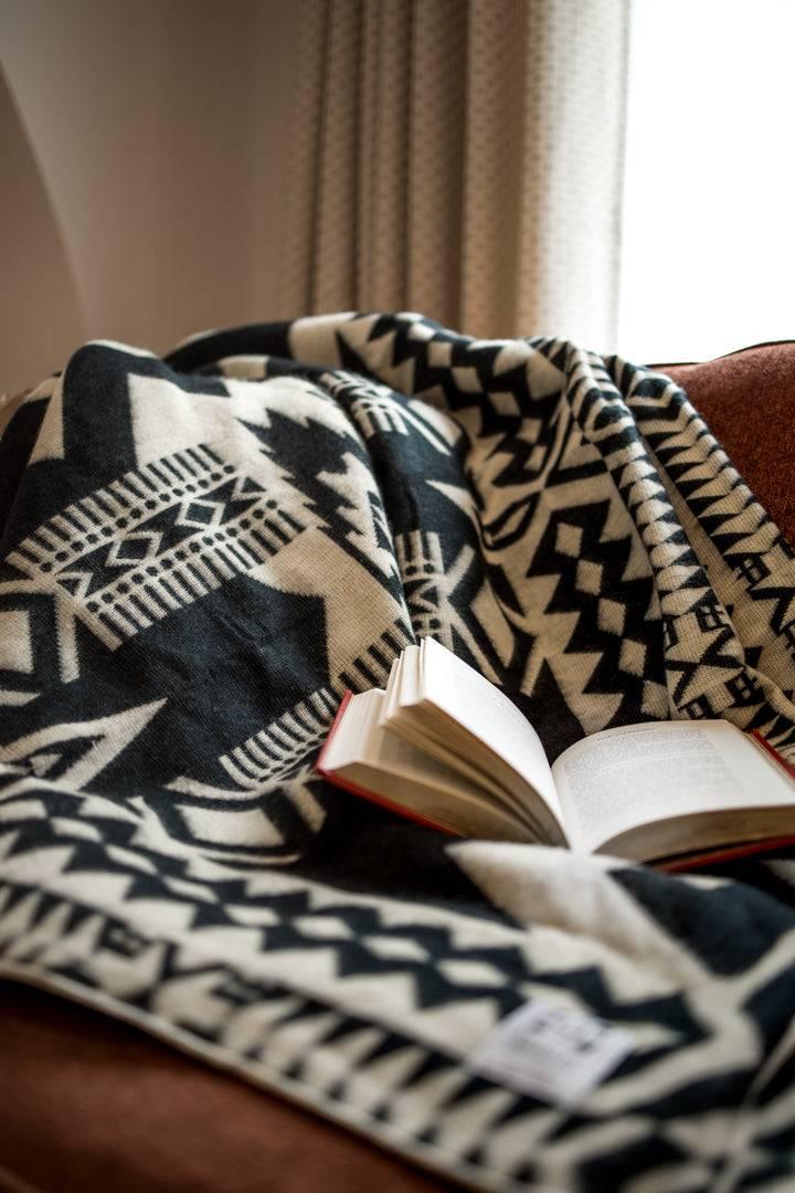 Beyond Borders Collective Awa blanket in a black-and-cream Andean geometric pattern.
