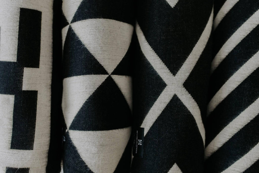 Handwoven Destino throw blanket in black with a cream linework band.