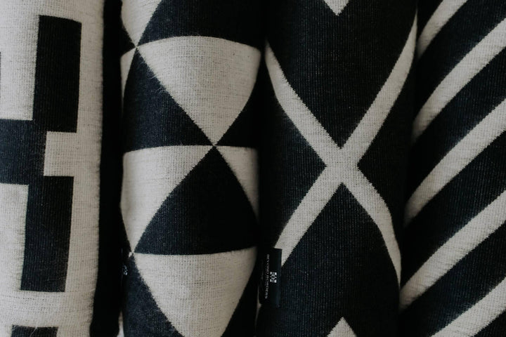 Handwoven Destino throw blanket in black with a cream linework band.