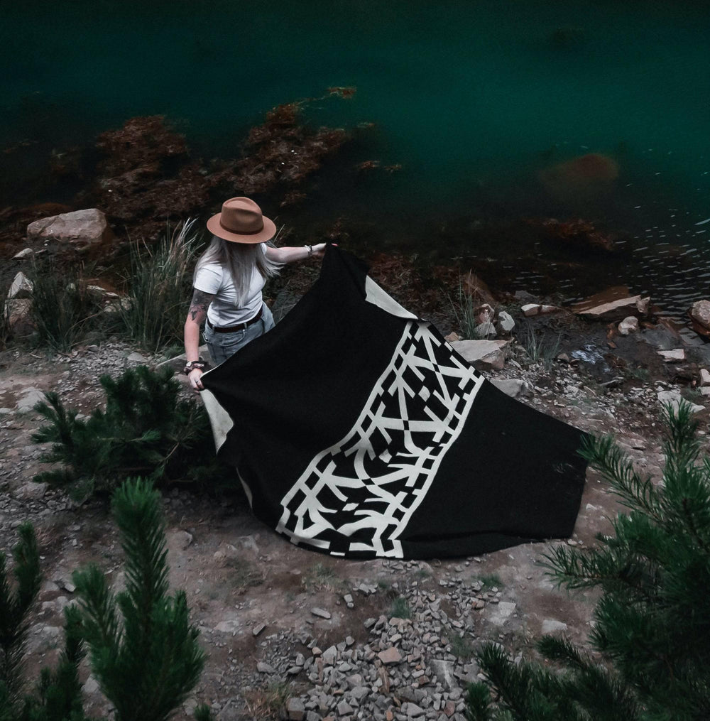 Black and cream Destino throw blanket with a modern abstract linework pattern.