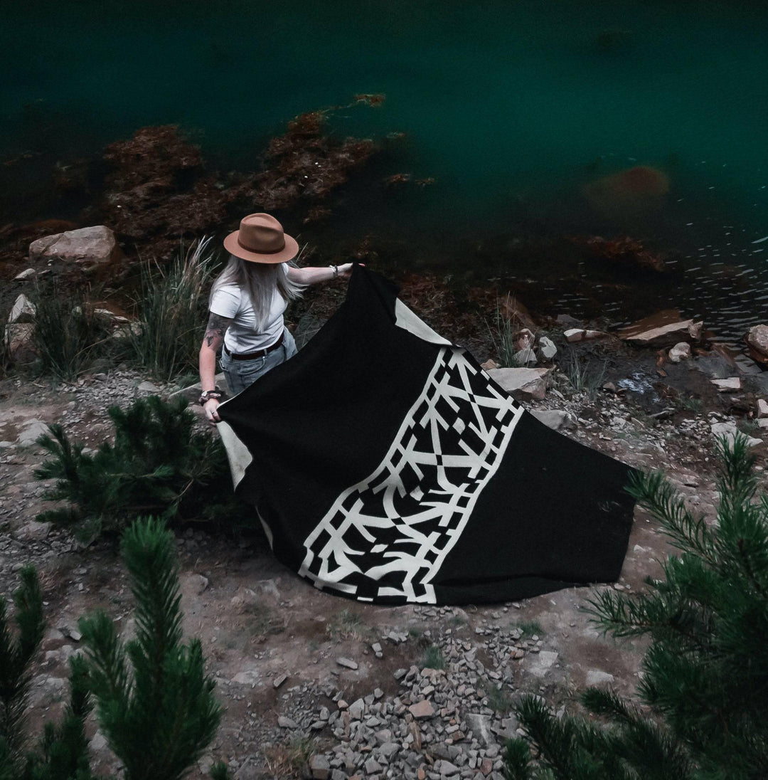 Black and cream Destino throw blanket with a modern abstract linework pattern.