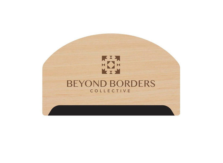 Small wooden lint and pill remover from Beyond Borders Collective, with a fine-toothed edge and engraved logo.