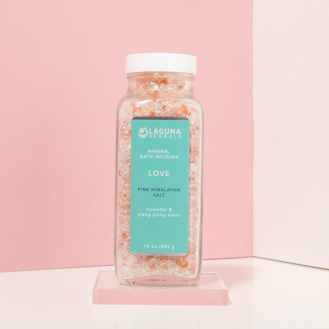 Pink Himalayan and Epsom bath salts in a glass bowl with a spoon.
