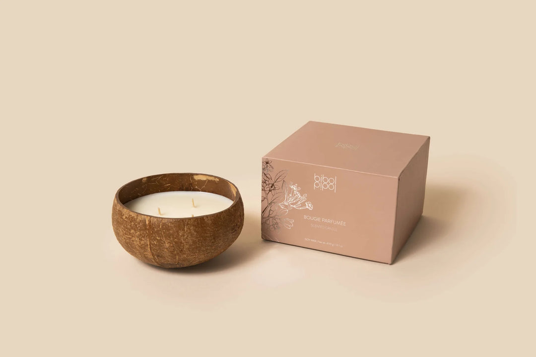 Soy wax candle in a coconut shell with a lit wick.