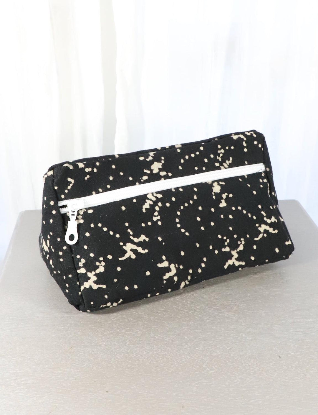 Black cotton block print toiletry bag with a floral and dot pattern.