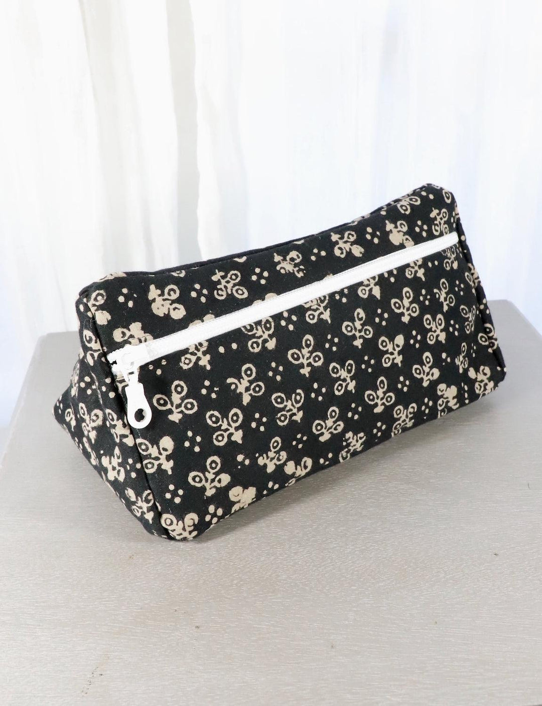 Black cotton block print toiletry bag with floral and dot patterns.