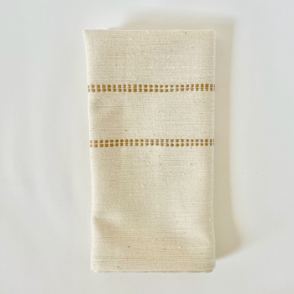 Natural cotton dinner napkin with an almond check band, folded