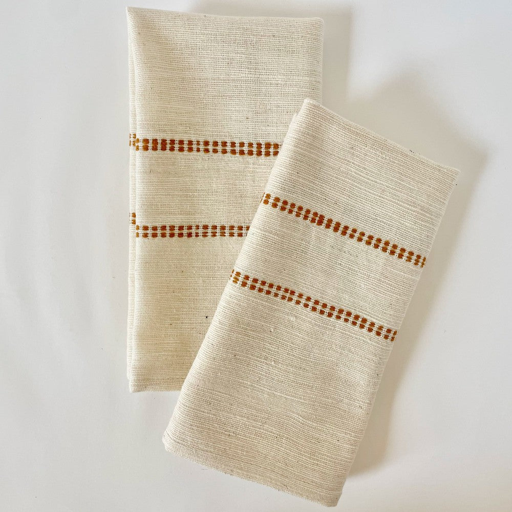 Pair of natural cotton dinner napkins with a bronze check band, folded