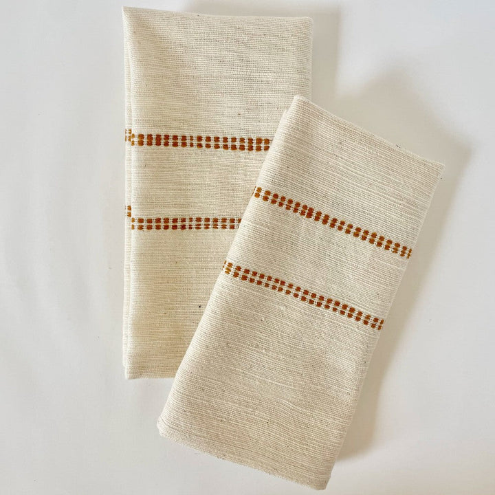 Pair of natural cotton dinner napkins with a bronze check band, folded