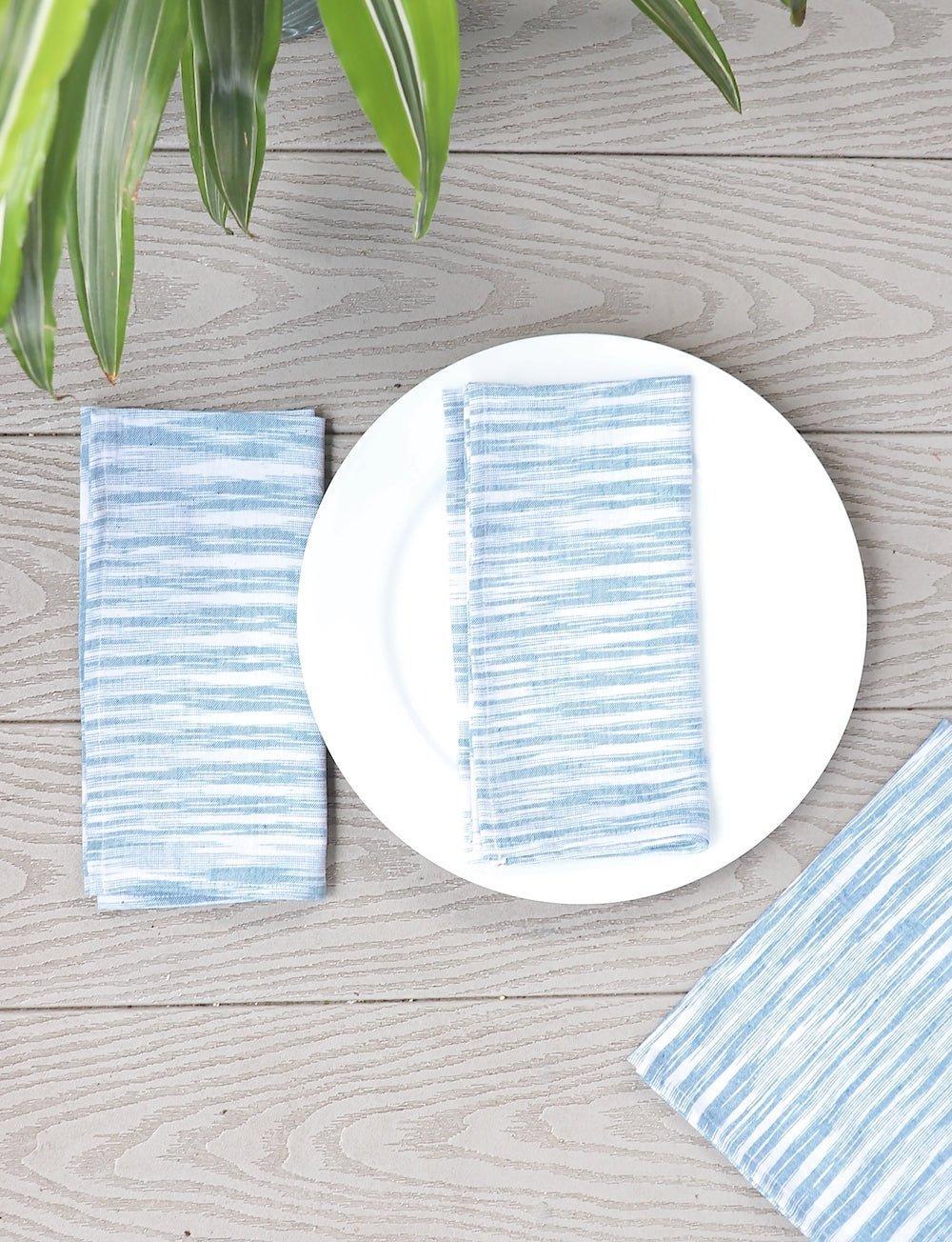 Set of four light blue handwoven cotton napkins, folded.