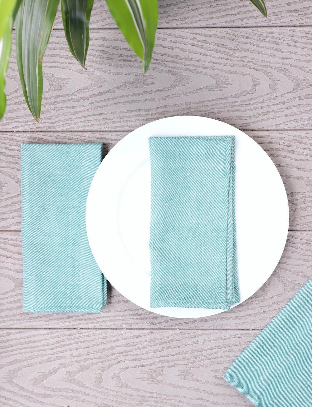 Set of four mint green cotton dinner napkins, folded.