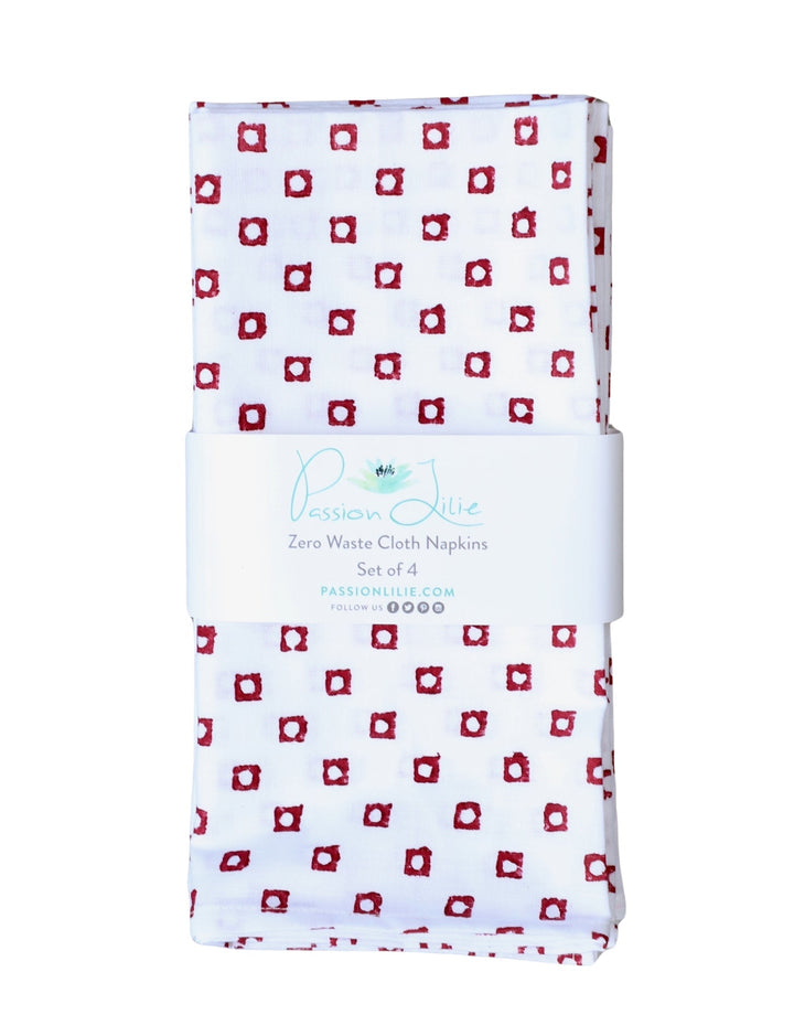 Set of four cotton napkins with a red square block print, folded.