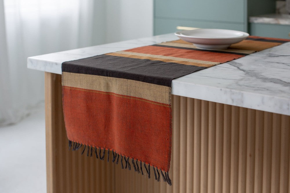 Copper color block table runner hanging off the end of a kitchen island