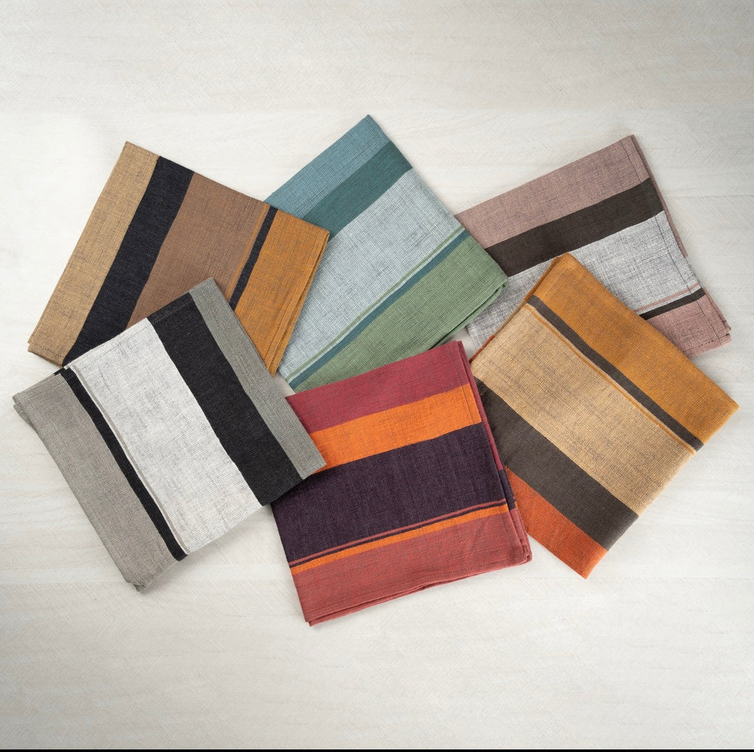 Handwoven color block napkins in all six colors scattered on a white surface