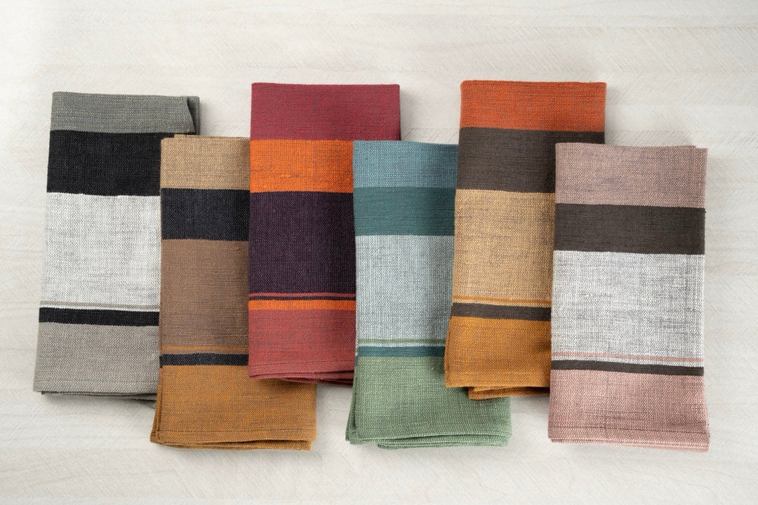 Color block cotton dinner napkins in steel blue, copper, blush, grey, mocha and plum, folded side by side