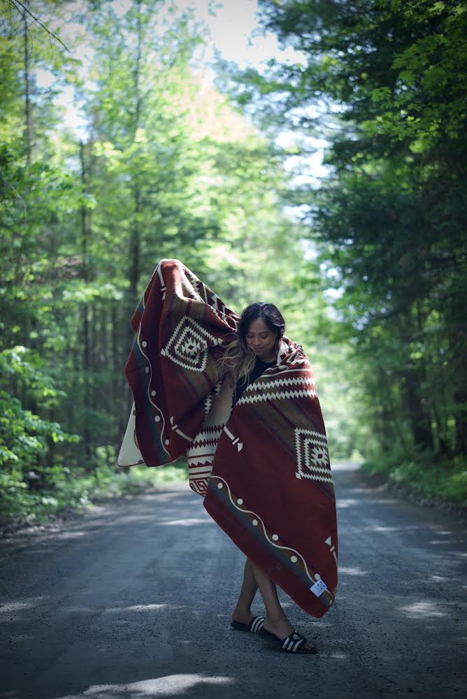 Achuar Autumn Andean blanket in rust with cream and olive geometric pattern, draped over a sofa.