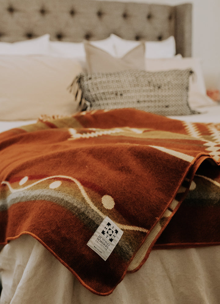 Handwoven Andean blanket in warm autumn rust and cream, made in Ecuador.