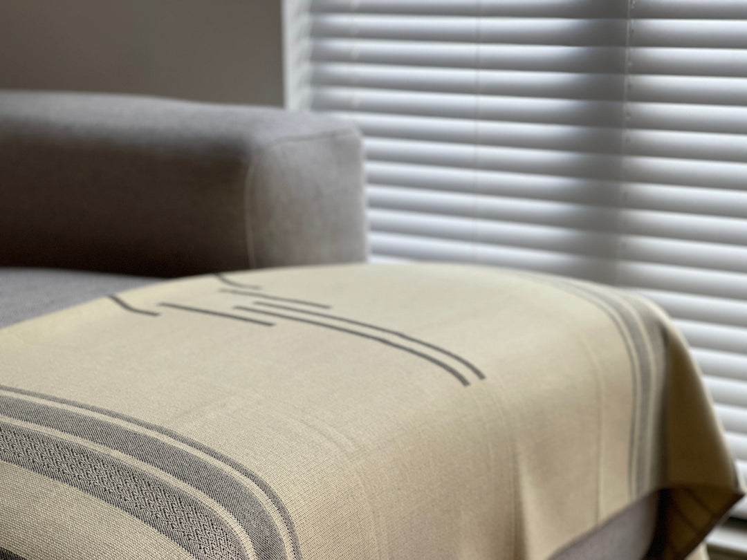 Equinoccio Cedar Brown striped throw with black-and-cream tasseled fringe.