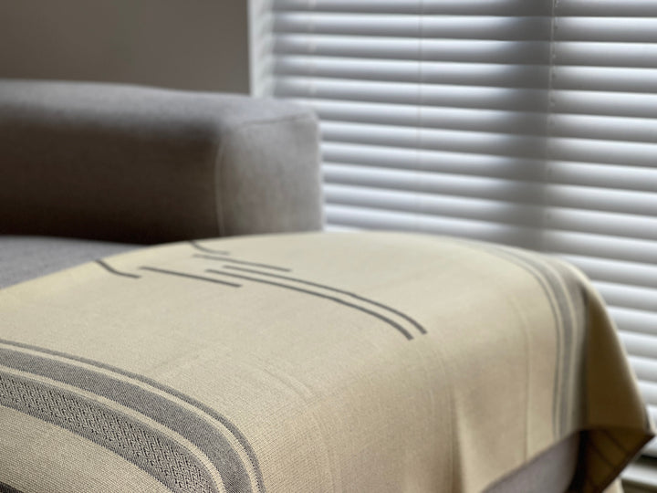 Equinoccio Cedar Brown striped throw with black-and-cream tasseled fringe.