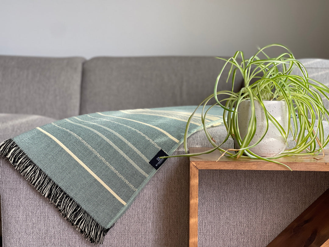 Beyond Borders Collective Equinoccio fringed throw in mint and natural striped weave.