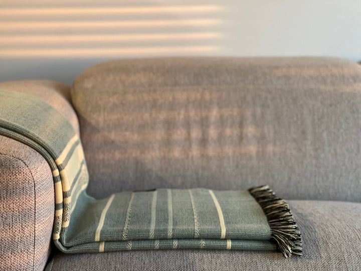 Cream and mint Equinoccio throw in 100% recycled acrylic, 70 by 55 inches.