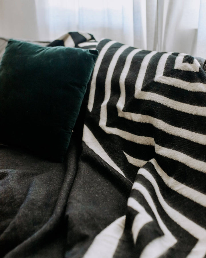 Black and cream Paramo blanket shown folded with the geometric weave visible.