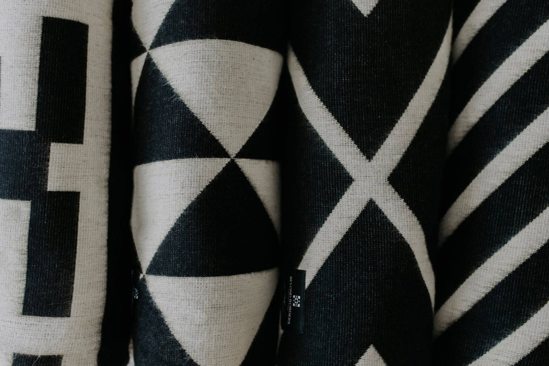 Handwoven Paramo throw blanket in bold black and cream, folded.