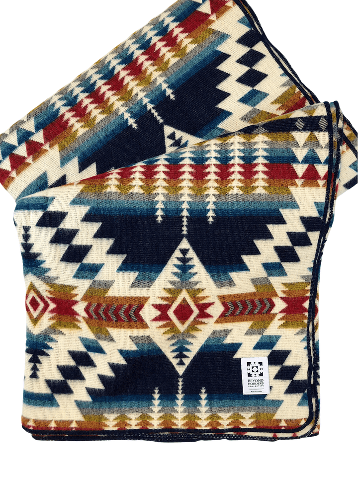 Handwoven Andean throw blanket in cream with a navy, red, teal, and gold geometric pattern.