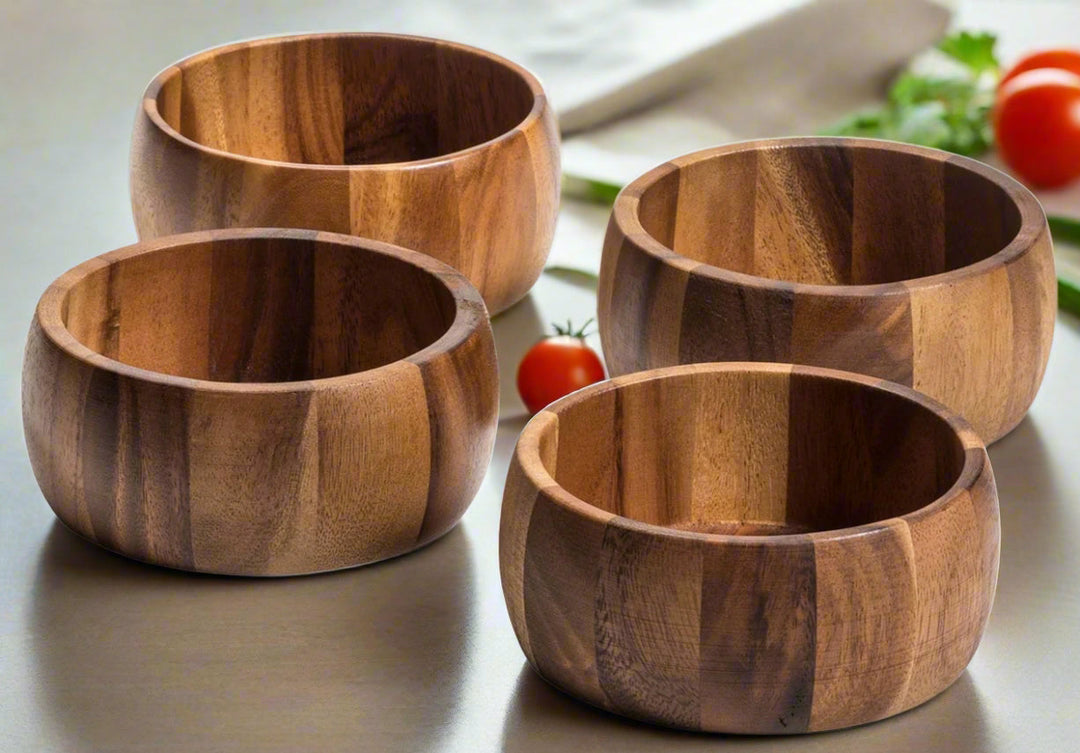 Set of four individual acacia wood salad bowls with a natural rounded form.
