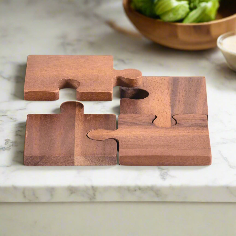 Four acacia wood puzzle piece coasters with natural grain, interlocking.