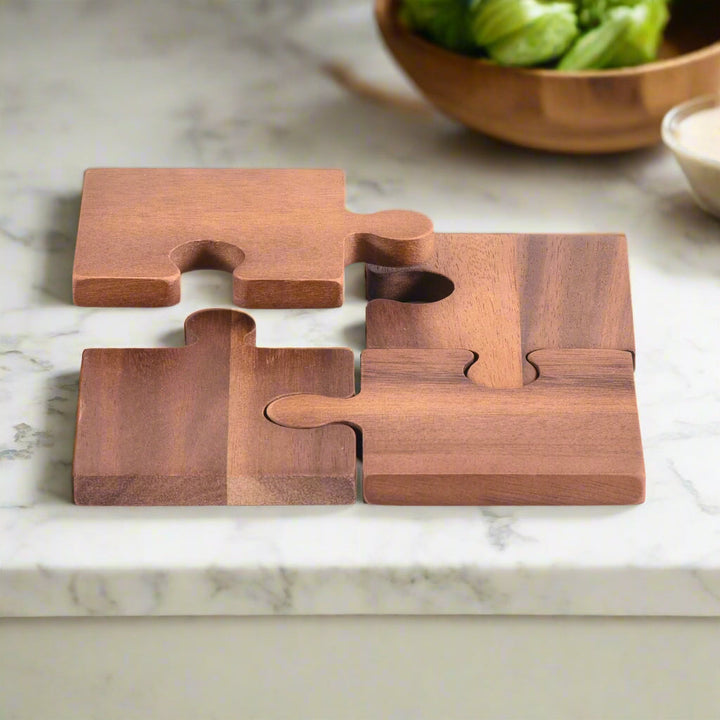 Four acacia wood puzzle piece coasters with natural grain, interlocking.
