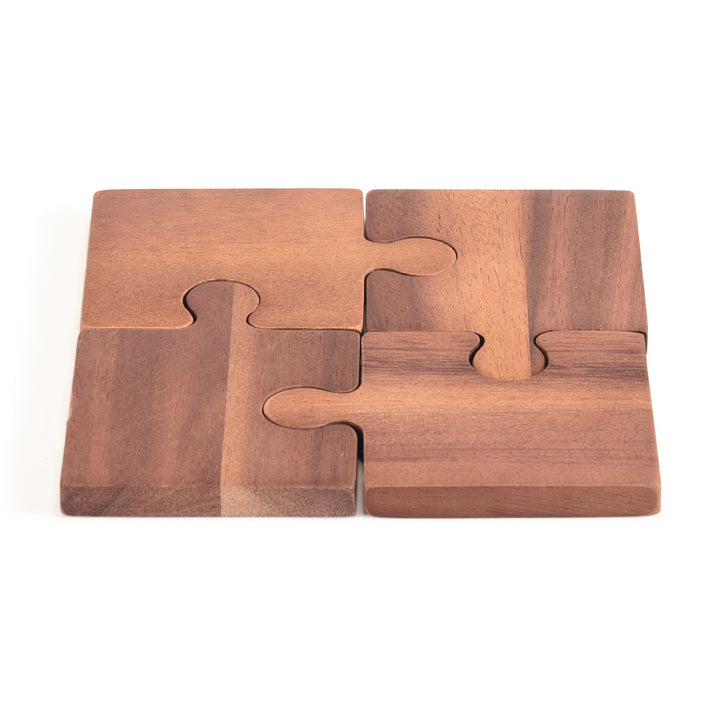 Four interlocking acacia wood puzzle piece coasters with natural grain.