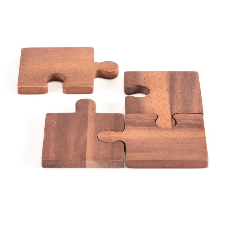 Set of four acacia wood puzzle piece coasters with an interlocking design.
