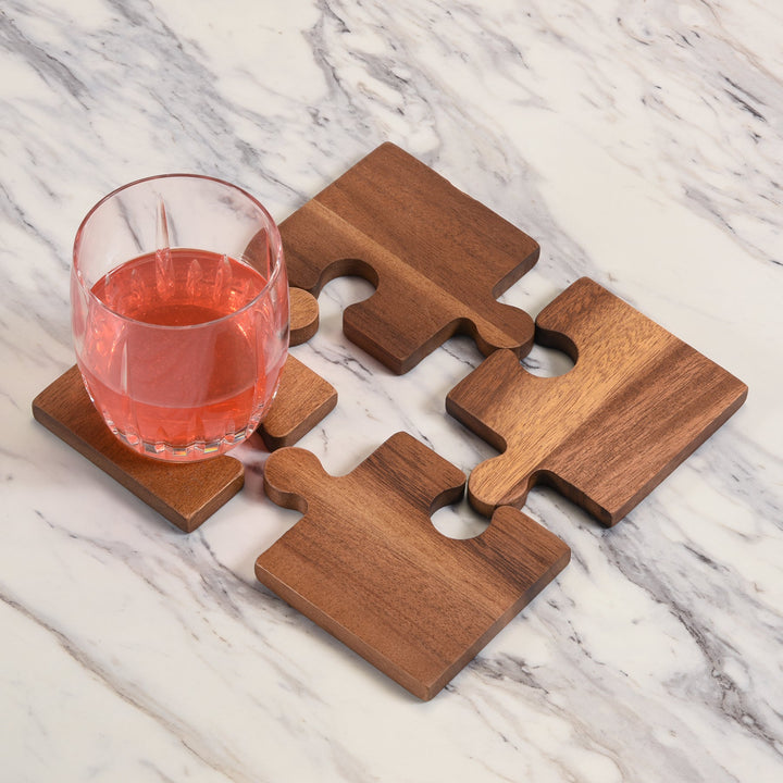 Set of four acacia wood puzzle piece coasters with natural wood grain.