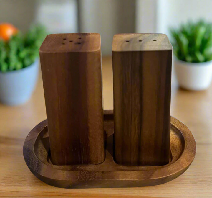 Acacia wood salt and pepper shakers with a matching base, natural wood finish.