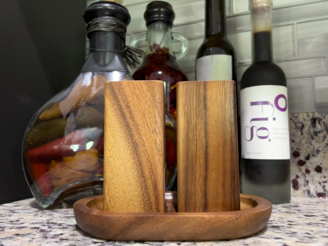 Acacia wood salt and pepper shakers on a matching base, smooth natural finish.